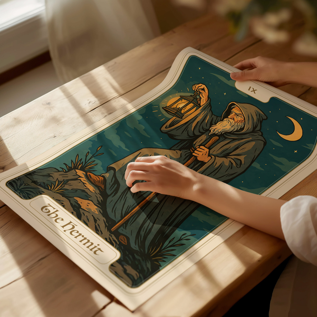 A person gently holds a Tarot card featuring The Hermit, depicting an elderly figure in a robe, holding a lantern and staff, set against a night sky with a crescent moon. The card rests on a wooden table.