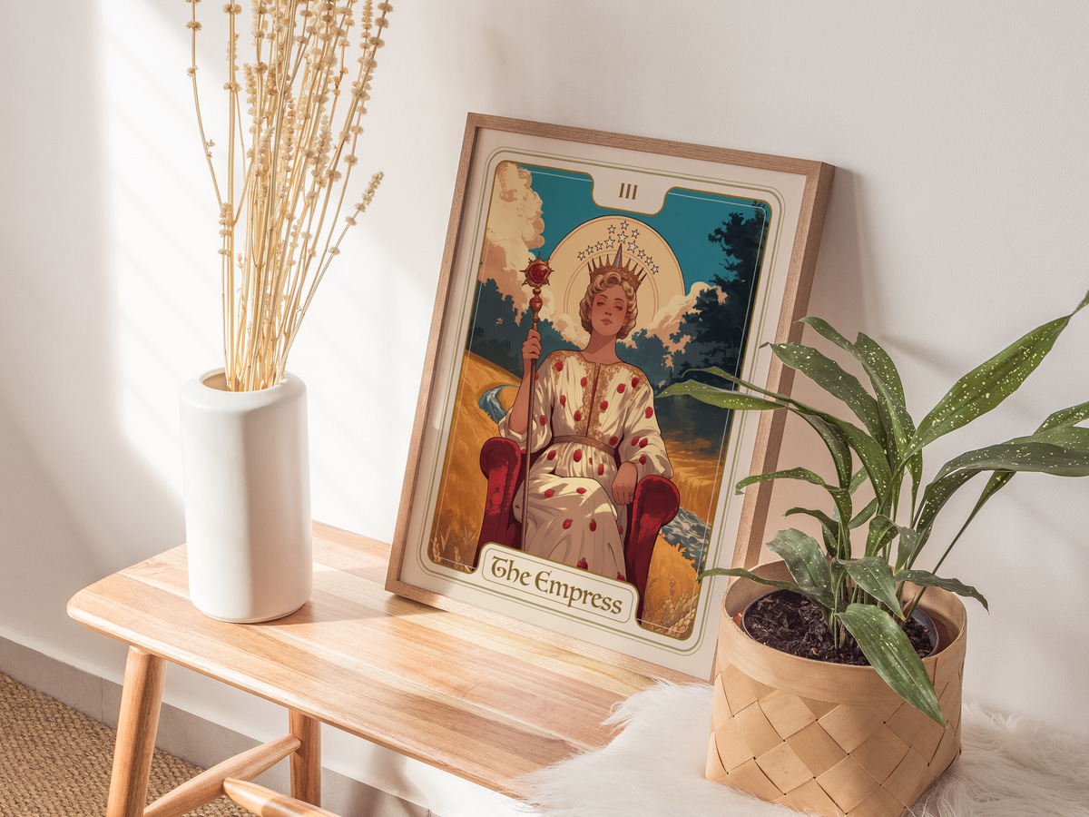 A framed art print titled The Empress features a regal figure seated on a throne, adorned in a flowing gown with a crown. The scene is complemented by a potted plant and a decorative vase, creating a serene indoor setting.