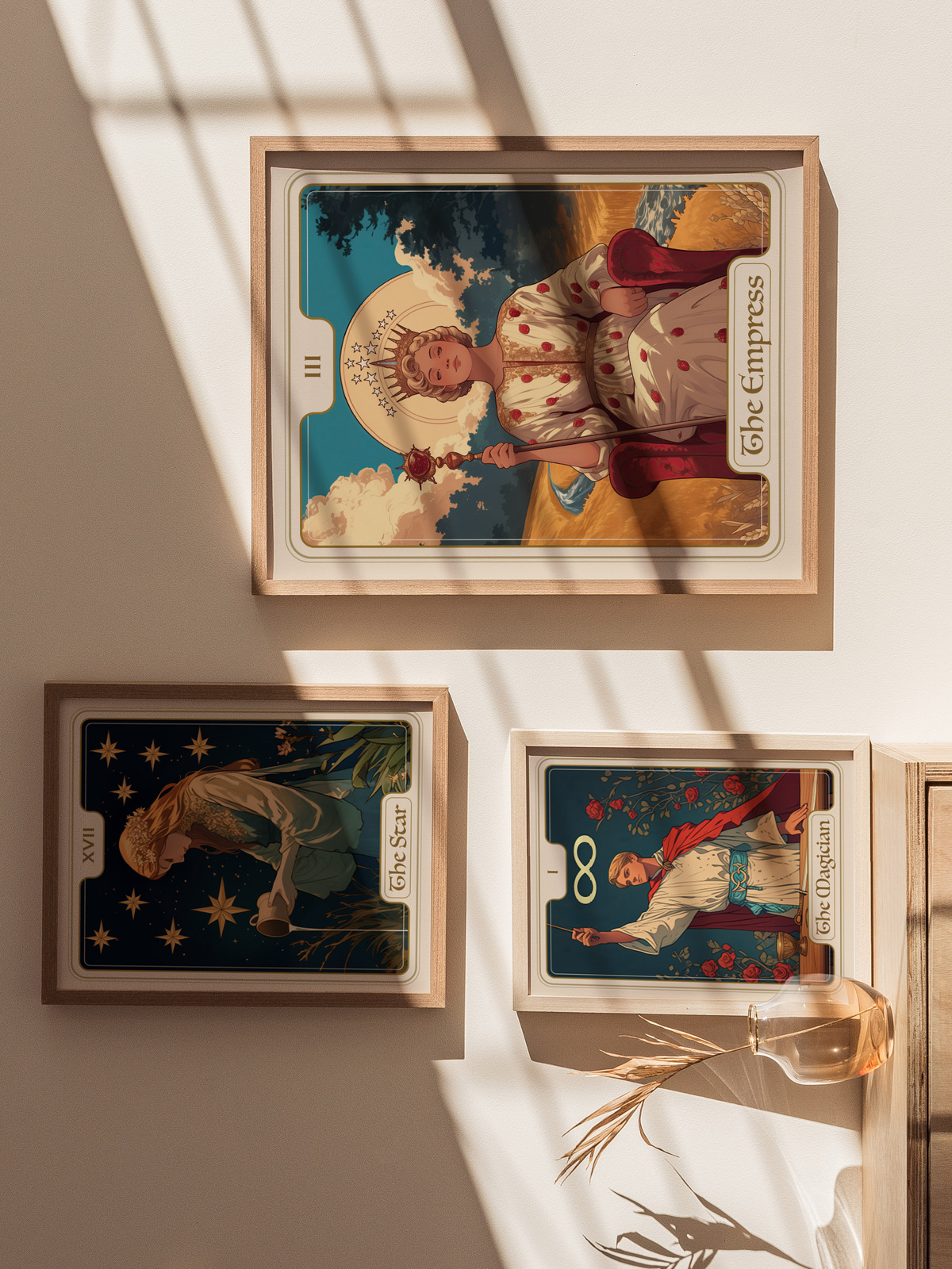 Three framed tarot cards are displayed on a light-colored wall. The top card, titled The Empress, features a regal figure surrounded by clouds and greenery, while the other two cards, The Star and The Chariot, showcase intricate.