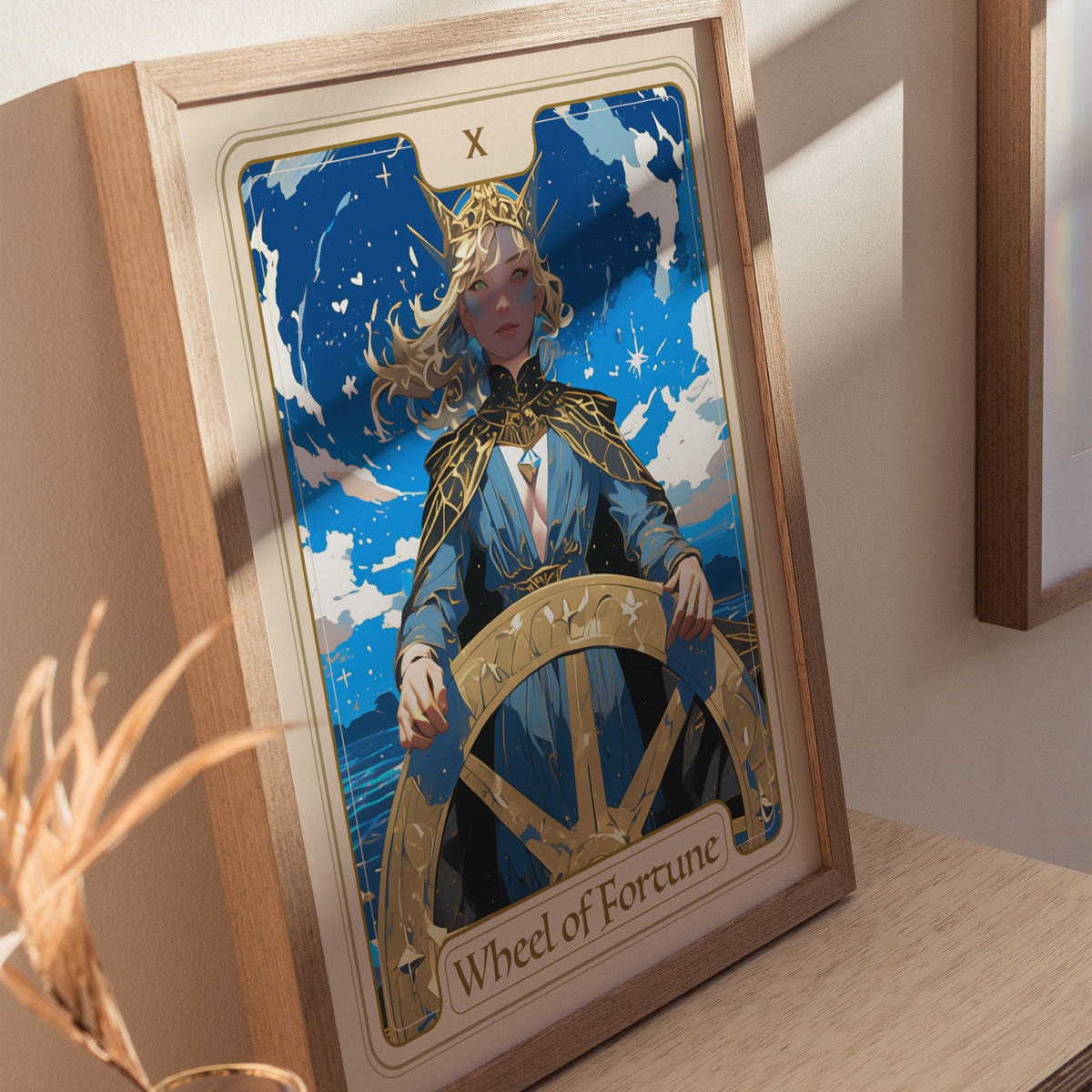A framed illustration of the Wheel of Fortune card features a woman with long hair wearing a golden crown and ornate clothing, standing behind a large ships wheel.