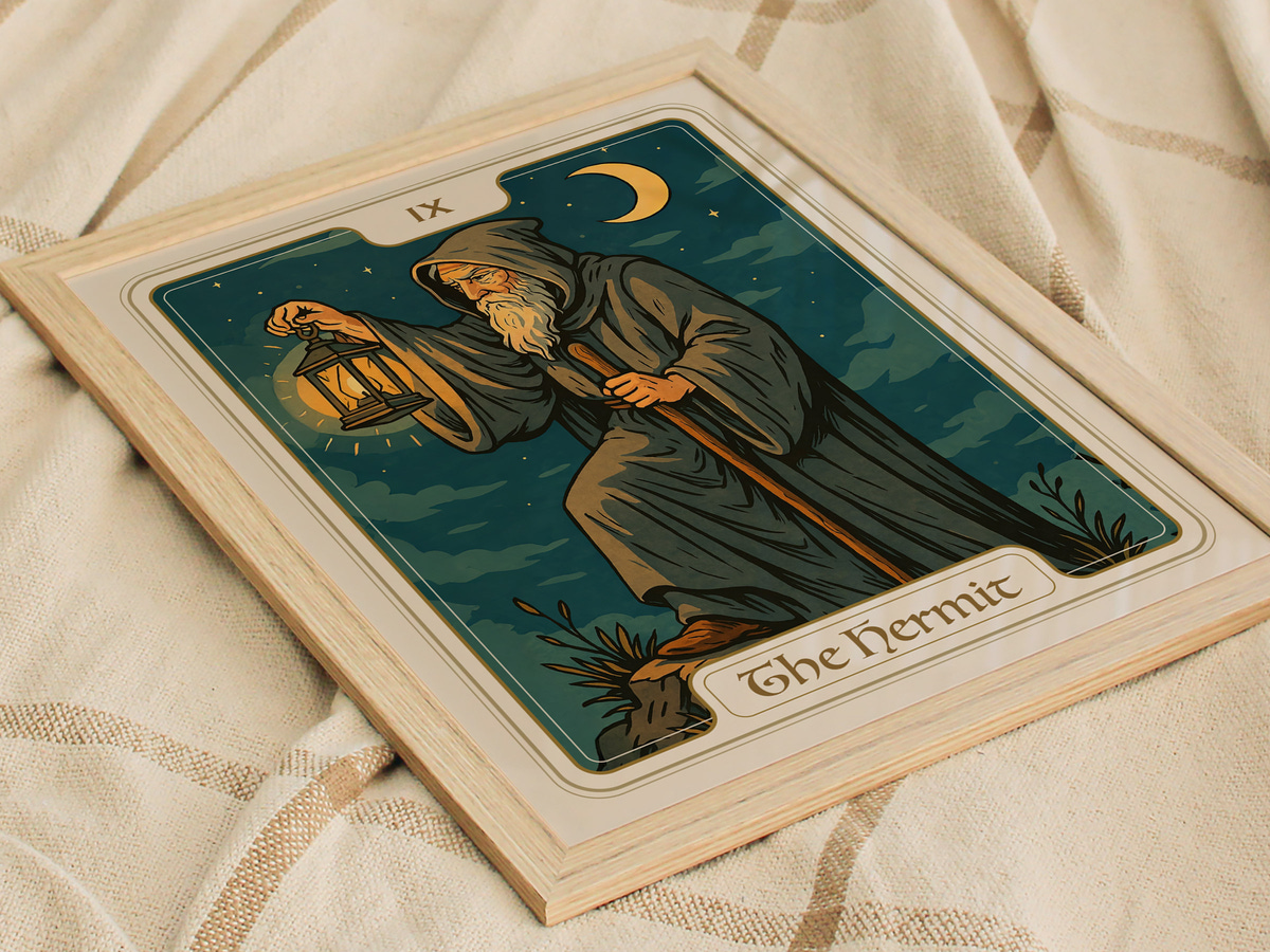 A framed illustration of The Hermit tarot card, featuring a robed figure holding a lantern while standing on a rocky terrain under a crescent moon. The design incorporates deep blues and greens, creating a mystical atmosphere.