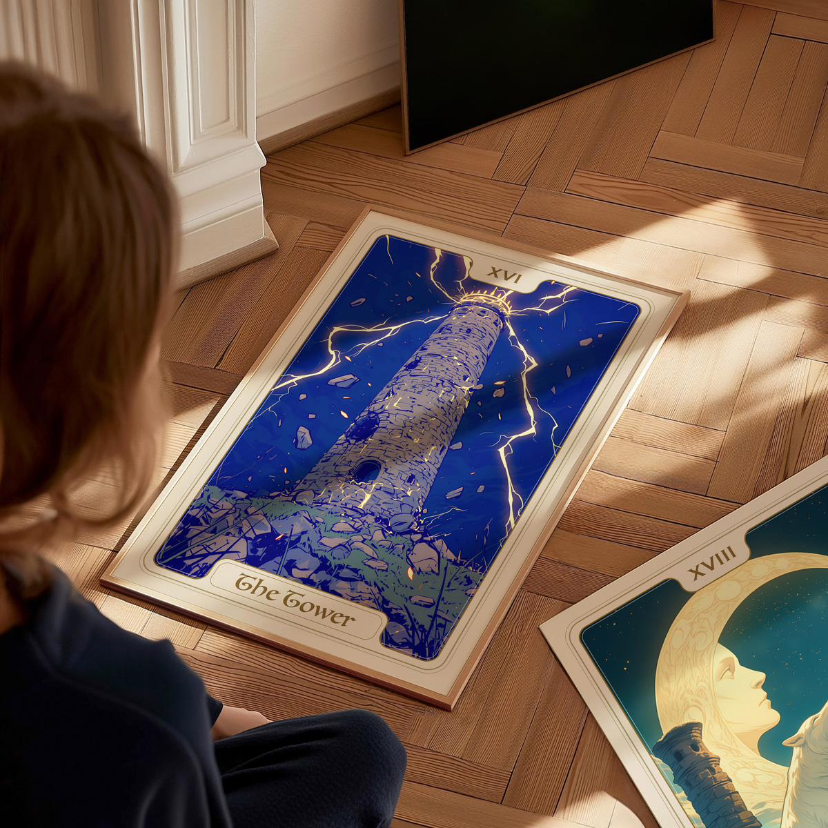 A child sits on a wooden floor, gazing at a large illustrated card titled The Tower, featuring a tall, crumbling tower struck by lightning against a deep blue background. Nearby, another card displays a moonlit scene with faces.